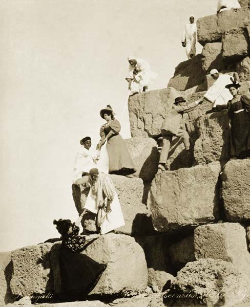Tourists ascending the pyramids with native guides (b/w photo)  od English Photographer