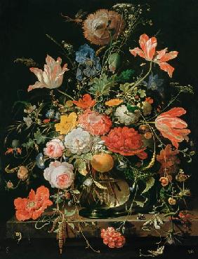 A glass with flowers and orange branch