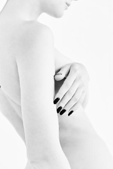 body parts of a naked girl torso and hand pressing her breasts with a black manicure on her nails
