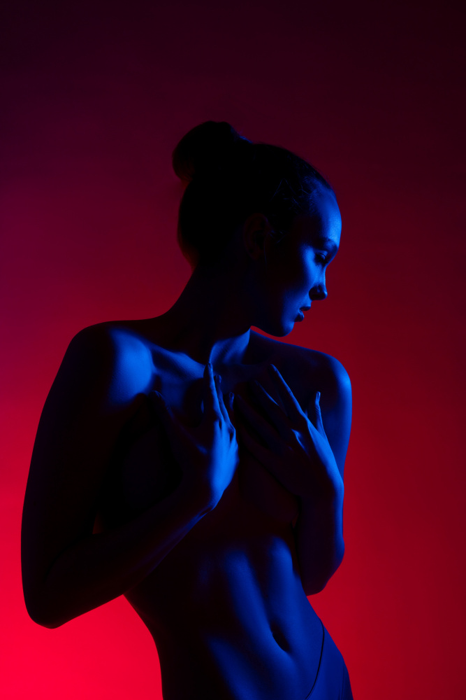 Young woman in casual clothes standing under neon light od Andrey Guryanov
