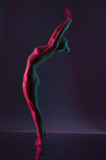 Young naked woman dance against dark purple background