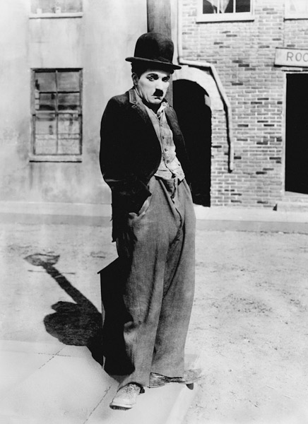 A dog 's life by and with Charlie Chaplin , standing in a street, hands in pockets. Los Angeles od English Photographer, (20th century)