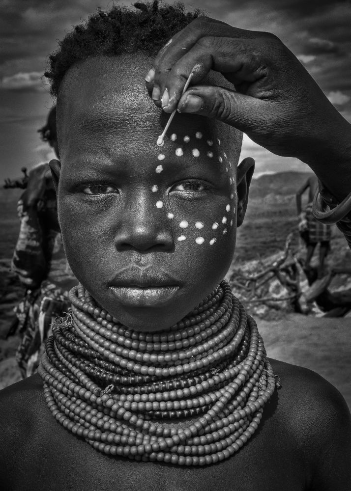 Painting the face of a karo tribe girl (Omo Valley-Ethiopia) od Joxe Inazio Kuesta
