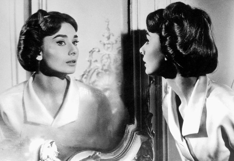 Actress Audrey Hepburn looking at her reflection in the mirror od 