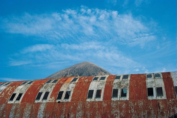Rusted roof of a deserted warehouse with the breast of a mountain (photo)  od 