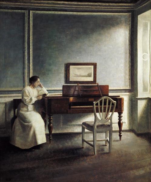 Woman, reading next to a piano in a book.